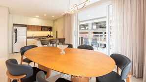 A modern dining area with a wooden oval table, black chairs, and a hanging light fixture. - Apt w/ Barbecue Grill 500m From the Beach Tdf0302 (Itapema)