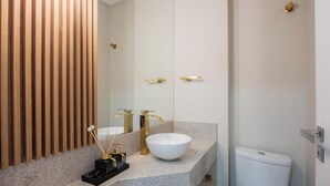 A modern bathroom with a wooden panel wall, a white sink with gold fixtures, and a white toilet. - Apt w/ Barbecue Grill 500m From the Beach Tdf0302 (Itapema)