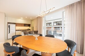 A modern dining area with a wooden oval table, black chairs, and a hanging light fixture. - Apt w/ Barbecue Grill 500m From the Beach Tdf0302 (Itapema)