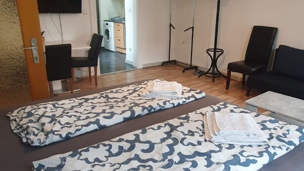 A room with a bed, a chair, a table, and a wardrobe.