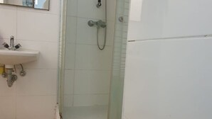 A bathroom with a sink, shower, and a mirror.