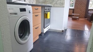 A compact kitchen with a washing machine, oven, and a small wooden table.