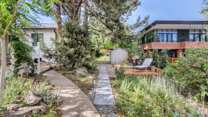 Una propiedad residencial con un sendero que conduce a una terraza, rodeada de plantas y árboles.