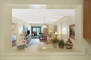 A spacious living area with a sofa, armchairs, a coffee table, and a dining table. There is a large window providing a view of the outdoors. - Beachfront 2BR + Studio with connecting door (Gulf Shores)