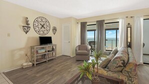 A living room with a television, sofa, and potted plants. - Beachfront 2BR + Studio with connecting door (Gulf Shores)