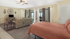 A spacious living room with a large bed, a sofa, a coffee table, and a ceiling fan. - Beachfront 2BR + Studio with connecting door (Gulf Shores)