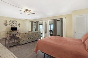 A spacious living room with a large bed, a sofa, a coffee table, and a ceiling fan. - Beachfront 2BR + Studio with connecting door (Gulf Shores)