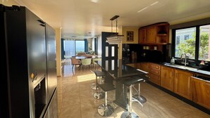 Een moderne keuken met een centraal eiland, barkrukken en uitzicht buiten door een raam.