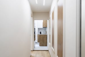 A narrow hallway leading to a kitchen with white cabinets and a wooden countertop. - [10 Min Cathedral] Refined Luxury (Firenze)