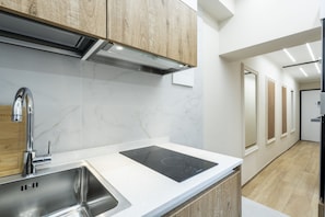 A modern kitchen with a stainless steel sink, a black induction cooktop, and wooden cabinets. - [10 Min Cathedral] Refined Luxury (Firenze)