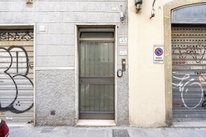 A building facade with a closed metal door, a no parking sign, and a number '33' on the wall. - [10min Cathedral] Refined Luxury (Firenze)