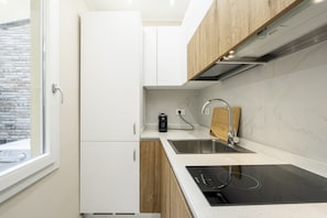 A modern kitchen with white cabinets, a black induction cooktop, a stainless steel sink, and a wooden countertop. - [10 Min Cathedral] Refined Luxury (Firenze)