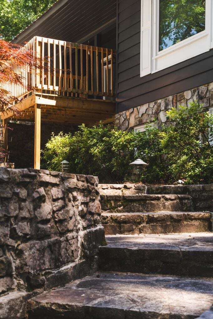 A stone staircase leading to a wooden deck with a stone wall in the foreground.