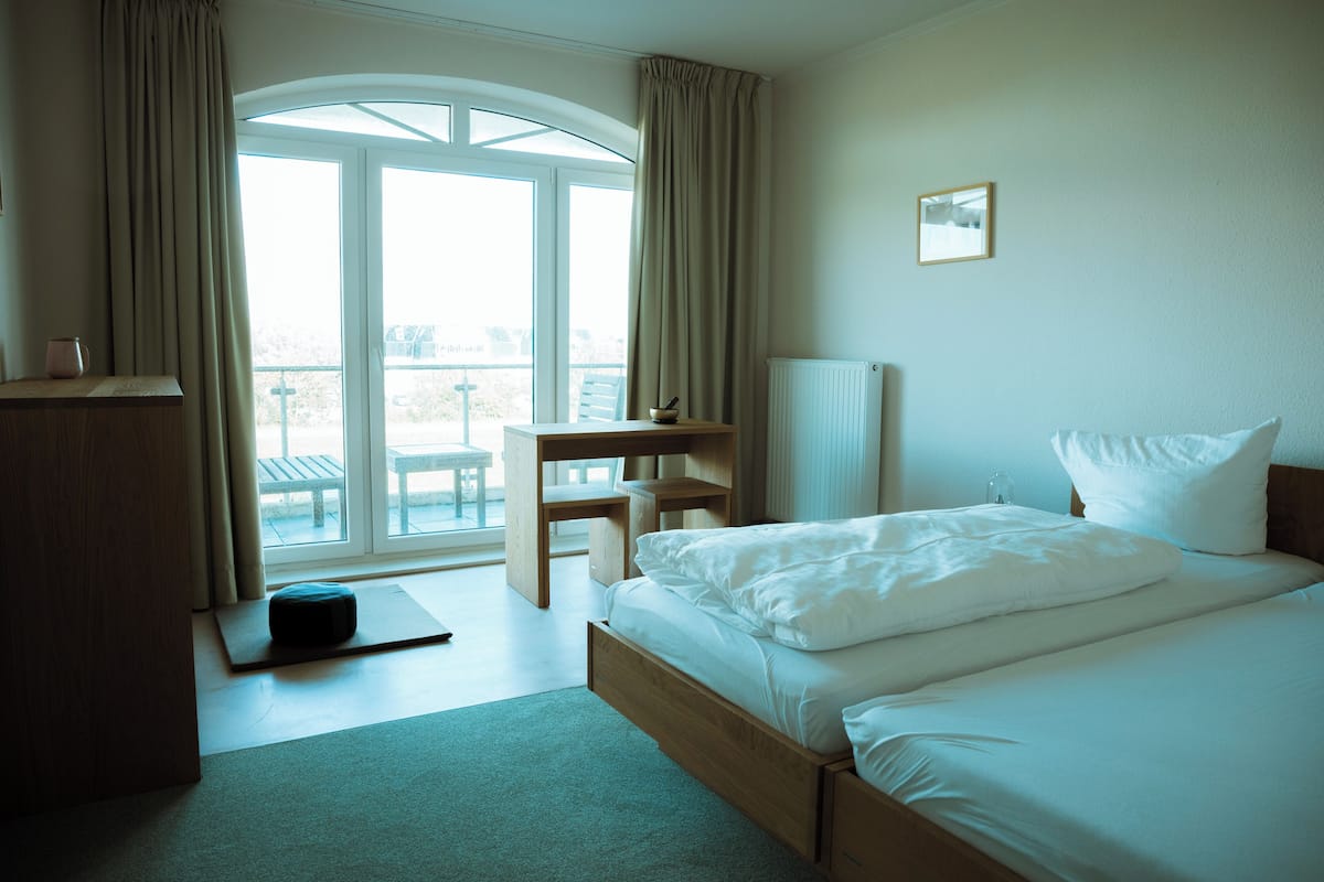 A hotel room with a bed, a desk, and a view of the outdoors.