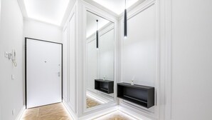 Een gang met een witte deur, spiegelwanden en inbouw zwarte planken.