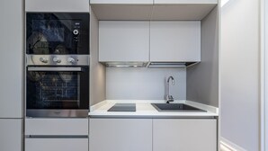 Een kleine keuken met inbouwapparatuur, een spoelbak en een raam.