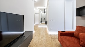 Een moderne woonkamer met een flatscreen televisie, een rode bank en een houten parketvloer.