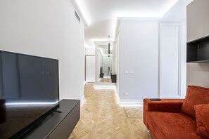 Ein modernes Wohnzimmer mit einem Flachbildfernseher, einem roten Sofa und einem Holzboden.