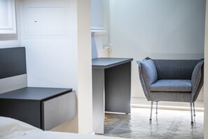 Une chambre moderne avec un lit, un bureau et un fauteuil gris.