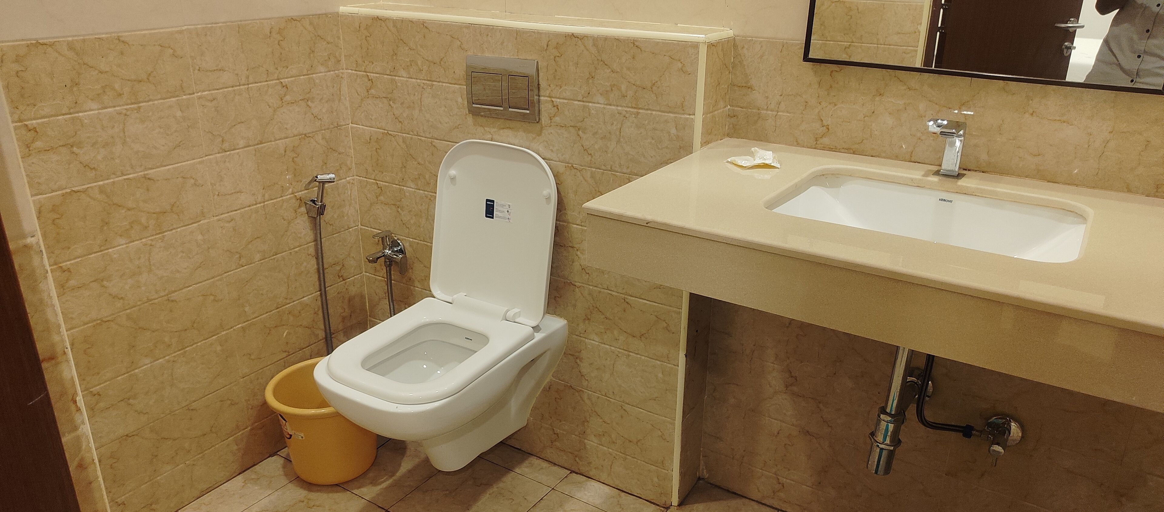 Ein Badezimmer mit Toilette, Waschbecken und einem gelben Eimer.