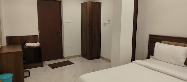 Un dormitorio con cama, armario, escritorio y cubo de basura.