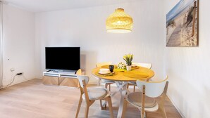 A dining area with a round table, chairs, a television, and a hanging light fixture. - Apartment 'Horsti' with Wi-Fi (Timmendorfer Strand)