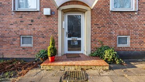 A brick building with a white door, a small window, and a potted plant on the steps. - Apartment 'Horsti' with Wi-Fi (Timmendorfer Strand)