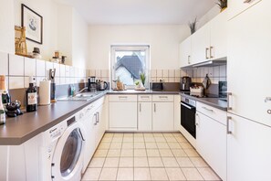 Eine moderne Küche mit Waschmaschine, Kaffeemaschine und einem Fenster mit Blick auf ein Haus.