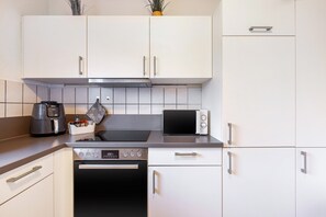 Eine moderne Küche mit weißen Schränken, einem Einbauofen, einer Mikrowelle und einer Kaffeemaschine.