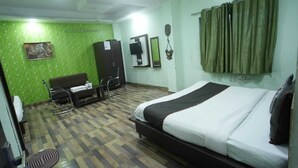 A hotel room with a bed, a chair, a desk, and a green wall. - Hotel Rameshwaram Inn (Rishikesh)