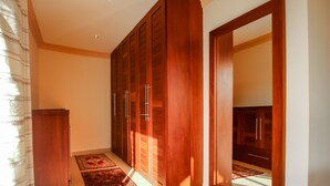 Une chambre à coucher avec une armoire en bois, un miroir et une moquette rouge.