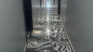 Un pasillo con suelo de mármol reflectante y paredes metálicas.