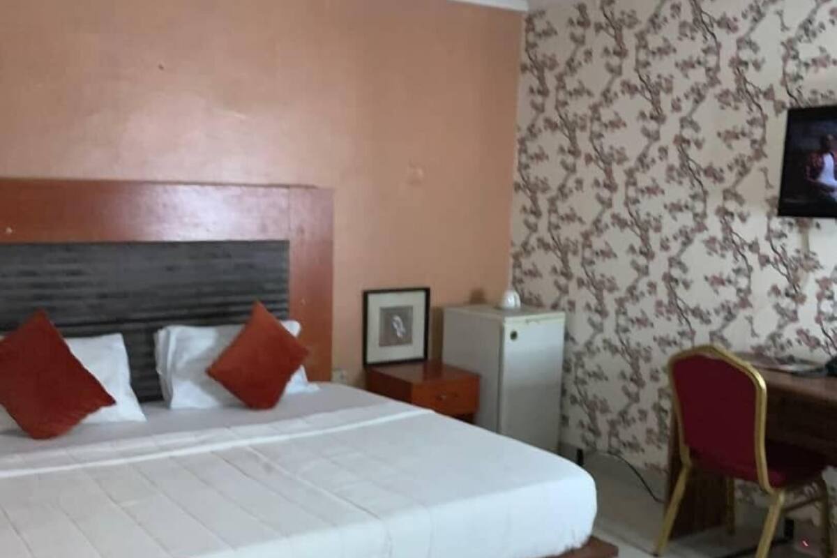 A hotel room with a bed, a desk, a chair, and a small table.