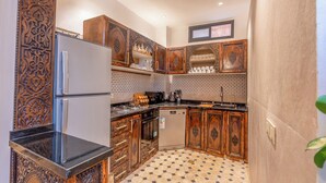 A compact kitchen with wooden cabinets, a built-in oven, and a refrigerator. - Elegant Riad Musée: Authentic Marrakech Charm in the Medina (marrakech)