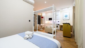 Una habitación de hotel con cama, una mesita, un sofá, una lavadora y un televisor.