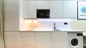 Una cocina compacta equipada con microondas, lavadora y lavaplatos.