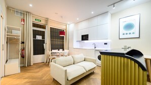 Una habitación de hotel moderna con un sofá, una mesita, un microondas y una lavadora.