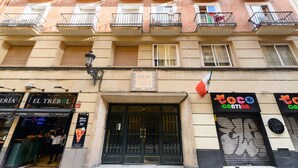 Un edificio de varios pisos con una pizzería en la planta baja, balcones con barandillas y un letrero que dice 'Coco Cratina'.