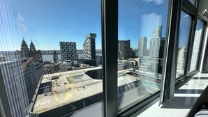 Un immeuble de grande hauteur doté de larges fenêtres donnant sur un paysage urbain, avec des bâtiments modernes et historiques.