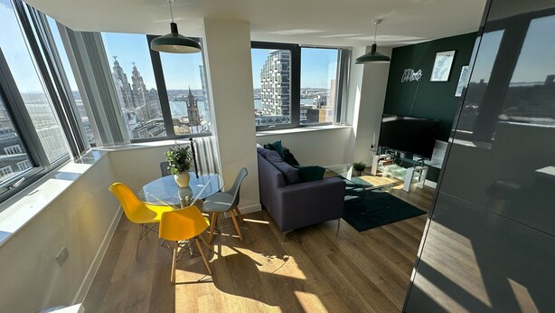 Un salon moderne avec un coin repas, de grandes fenêtres et une vue sur le paysage urbain.
