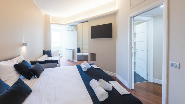 Une chambre d’hôtel dotée d’un grand lit, d’un téléviseur à écran plat fixé au mur et d’une porte donnant accès à une salle de bain.