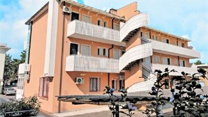 A multi-story building with balconies and a central staircase. - Central flat with terrace and parking (Bibione)