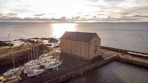 Un bâtiment situé sur la côte, avec un bateau amarré et une mer calme en arrière-plan.
