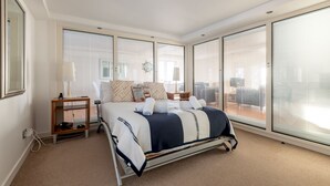 Une chambre moderne avec un grand lit, de nombreuses fenêtres et une petite table de chevet.
