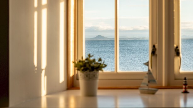 Une fenêtre donnant sur la mer et les montagnes.