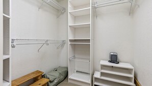 Un dressing accessible sans porte, doté d’étagères ouvertes, d’un banc et d’une petite table avec une bouilloire.