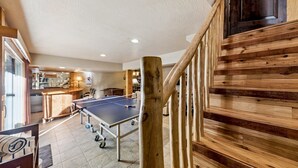 Une table de ping-pong dans une pièce aux murs en bois et avec un escalier.