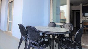Un coin repas comprenant une table ronde et six chaises, une porte-fenêtre coulissante et une vue sur l’intérieur.