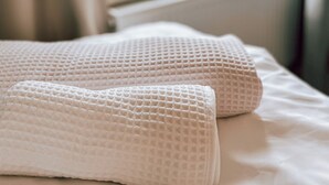 Een bed met witte beddengoed en twee gestructureerde kussens.
