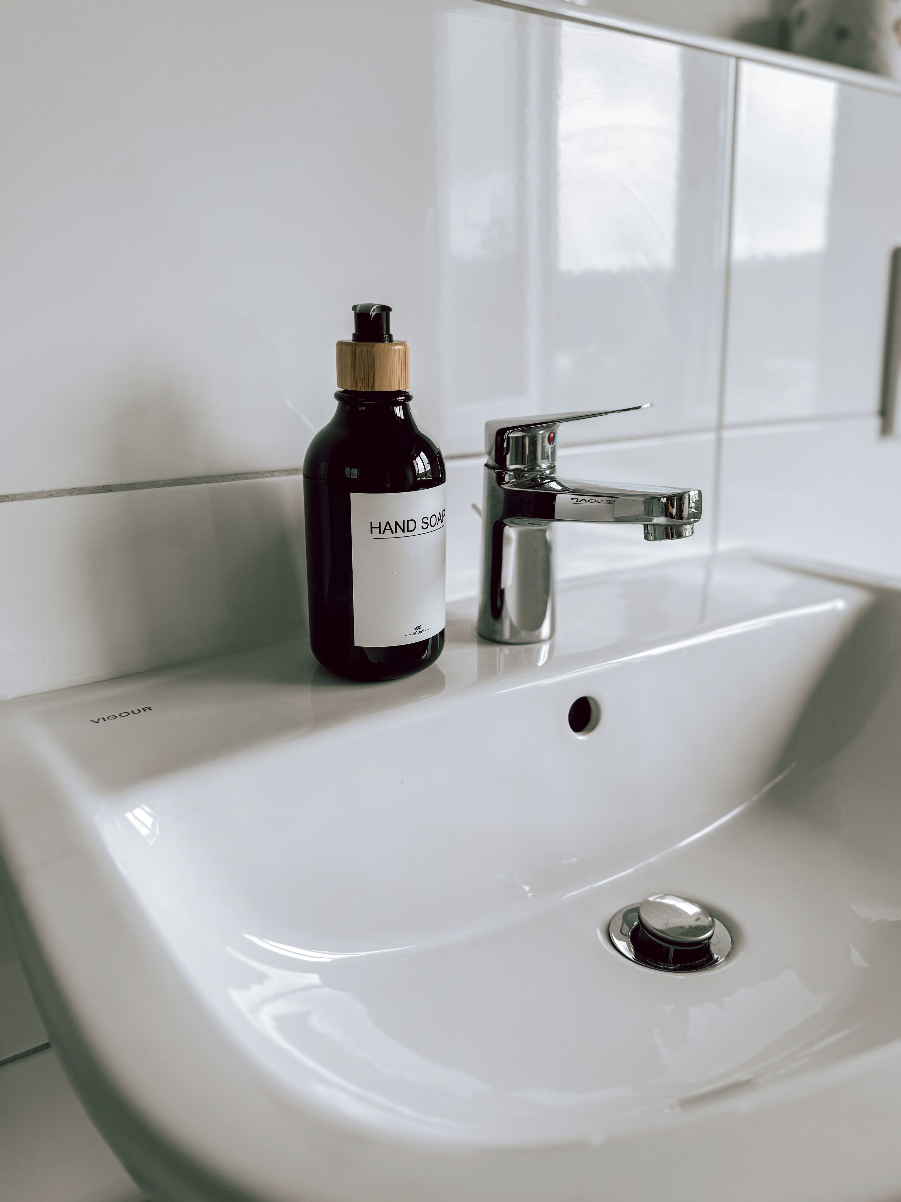 A white bathroom sink with a black hand soap bottle and a chrome faucet.